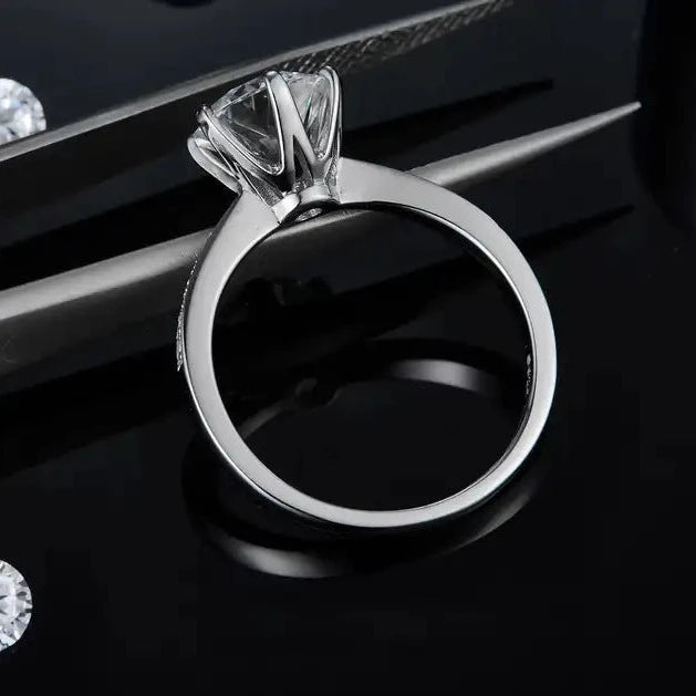 This sterling silver engagement ring features a stunning 2.00ct moissanite secured in a classic 6-claw Tiffany setting, with a band adorned with pave-set stones.