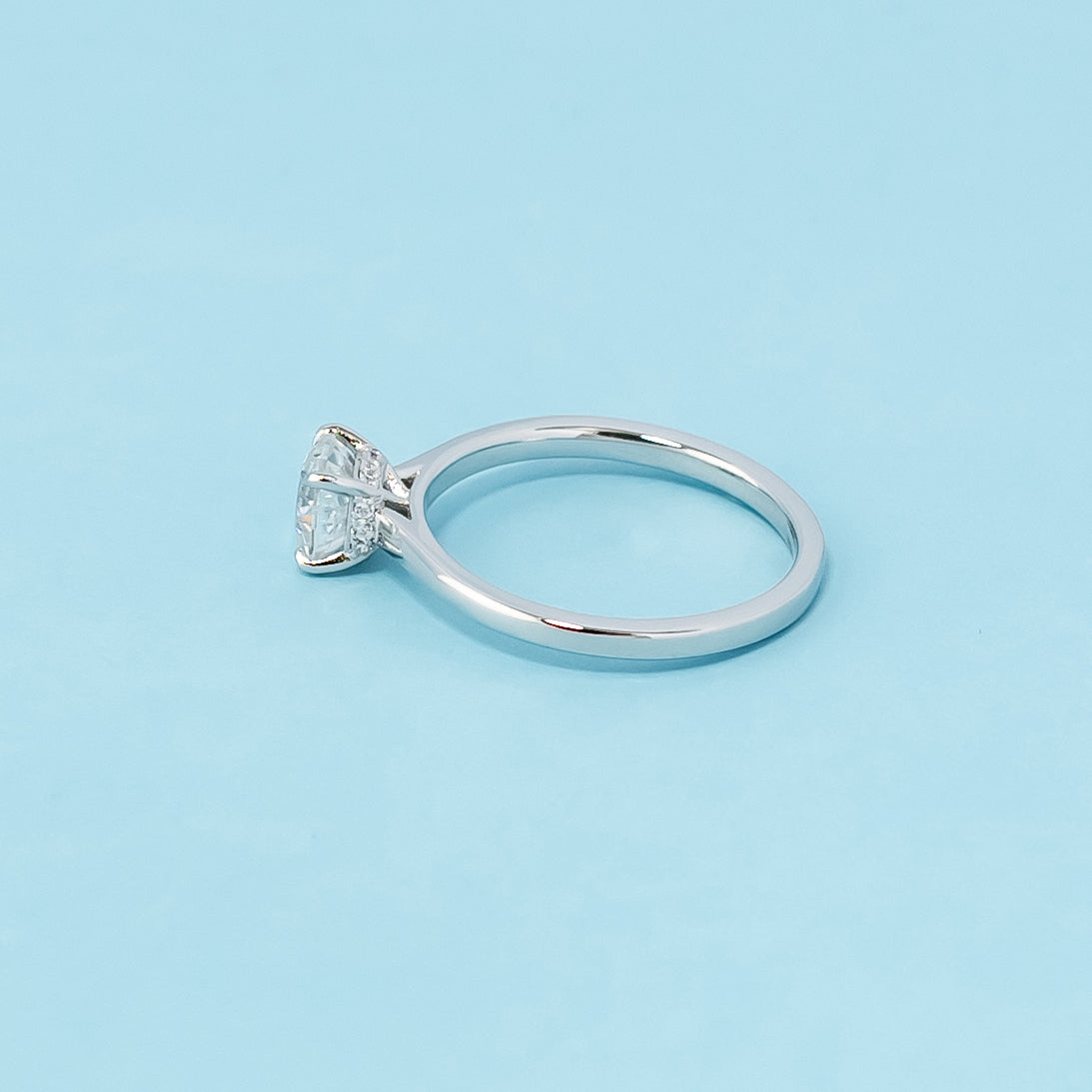 Modern and sophisticated engagement ring showcasing a cushion cut moissanite in a unique hidden halo design, crafted in 9ct white gold.