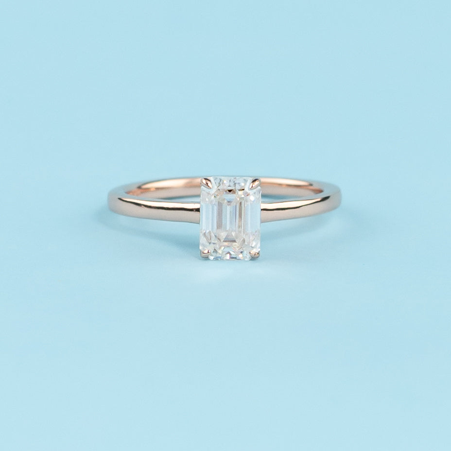 Elegant emerald cut moissanite engagement ring with a delicate hidden halo, set in warm 9ct rose gold.