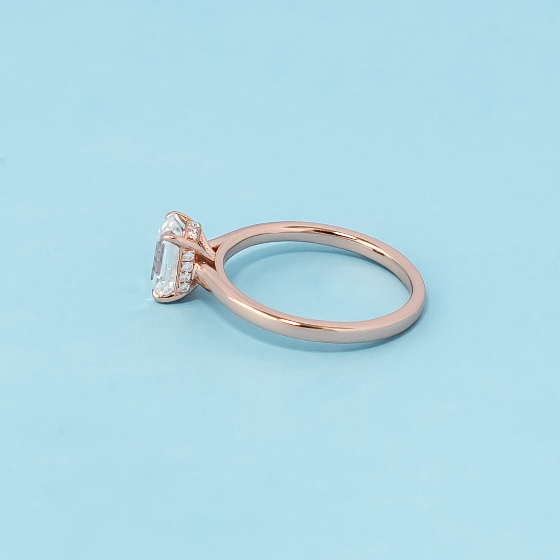 Stunning rose gold engagement ring featuring a sparkling emerald cut moissanite and a secret sparkle hidden halo design.