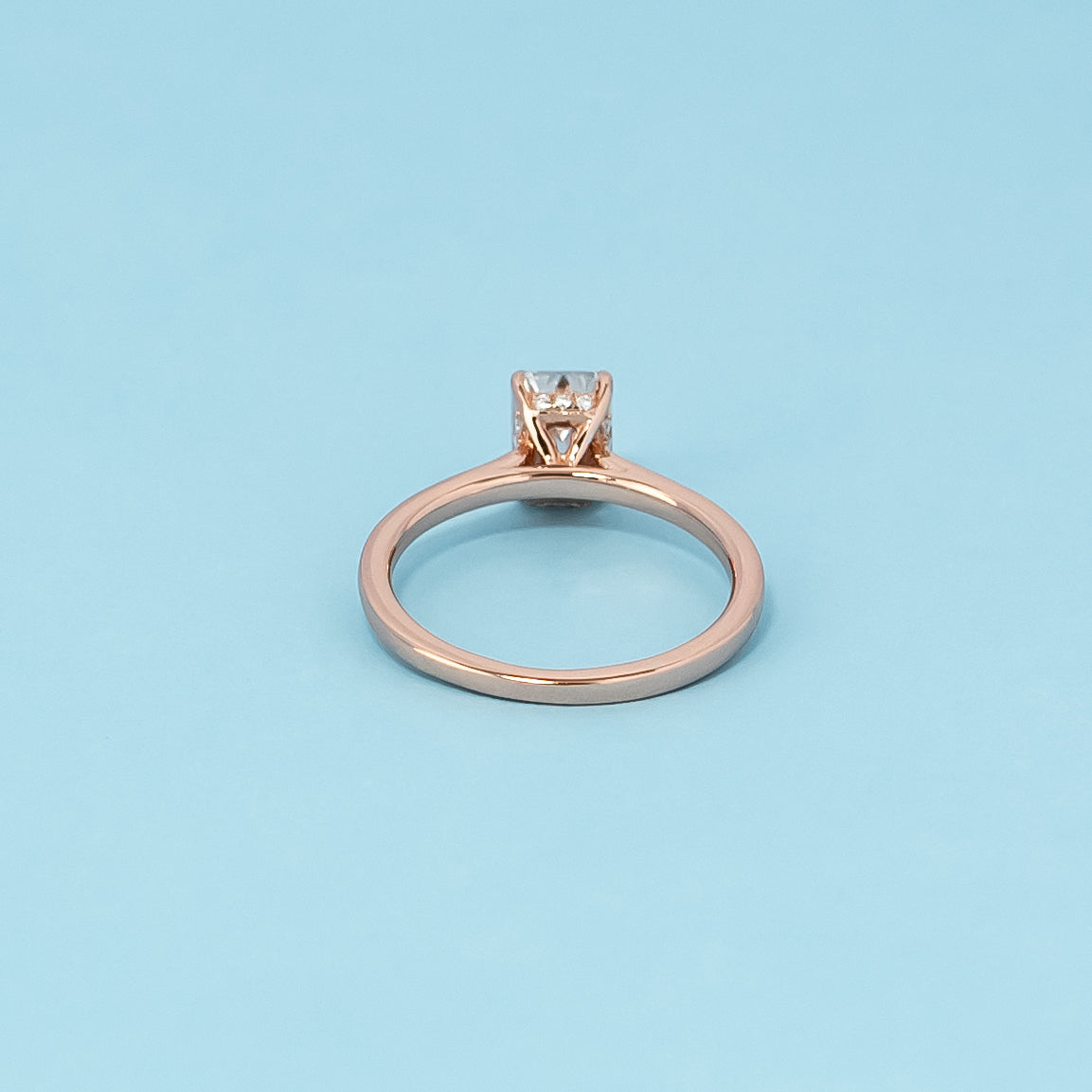 Luxurious 9ct rose gold engagement ring showcasing a brilliant emerald cut moissanite with a subtle and dazzling hidden halo.