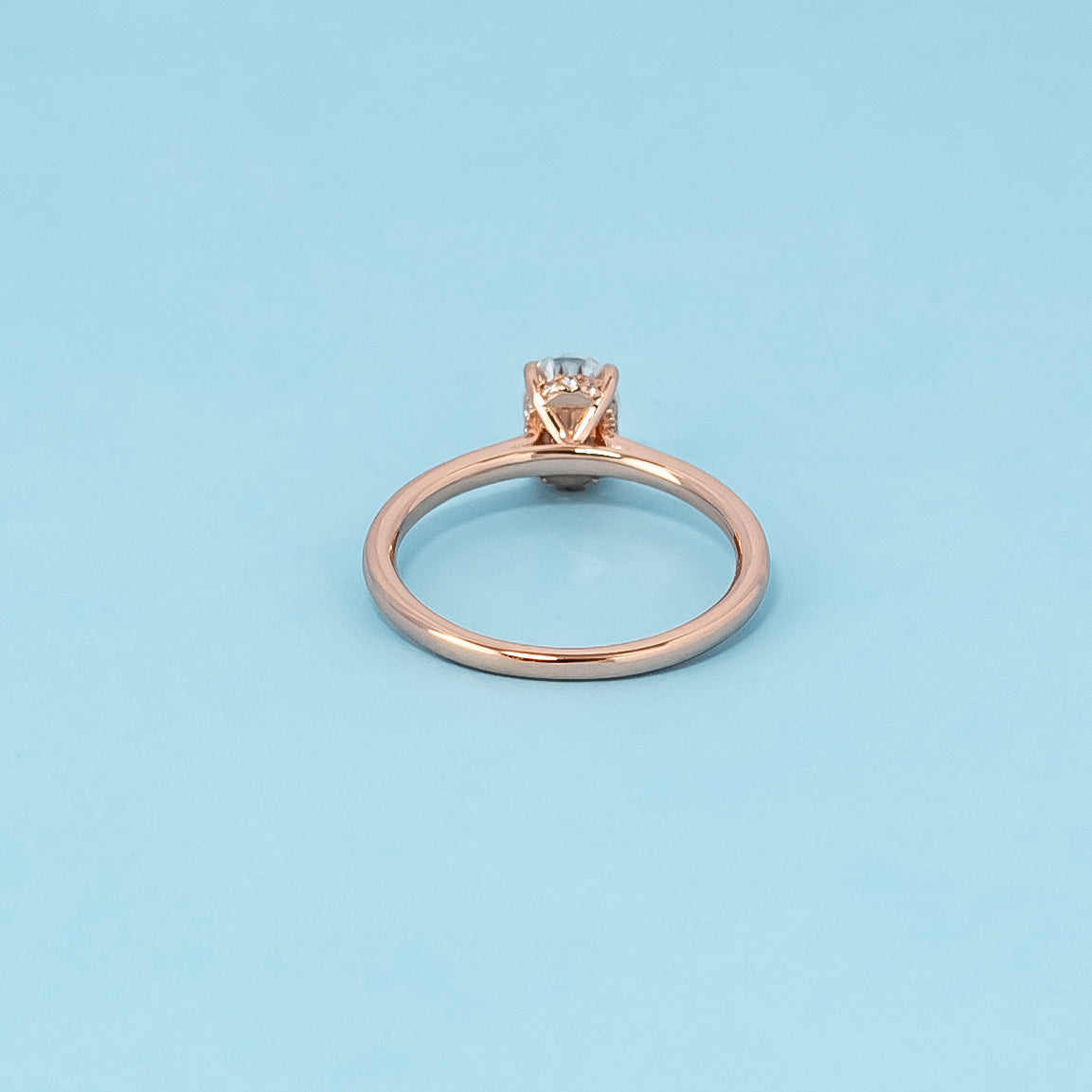 Luxurious 9ct rose gold engagement ring showcasing a brilliant oval cut moissanite with a subtle and dazzling hidden halo.