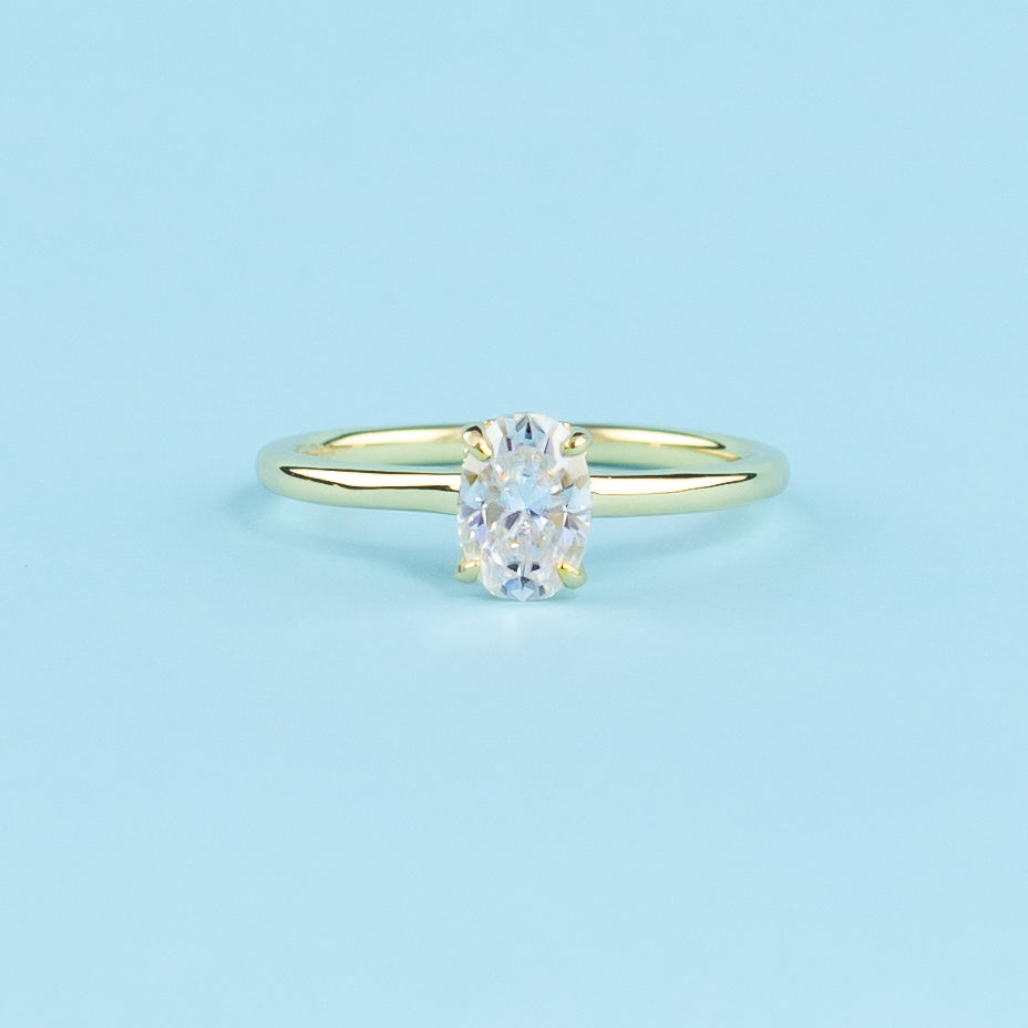 Discover the secret sparkle with this elegant ring, showcasing an oval moissanite enhanced by a hidden halo.