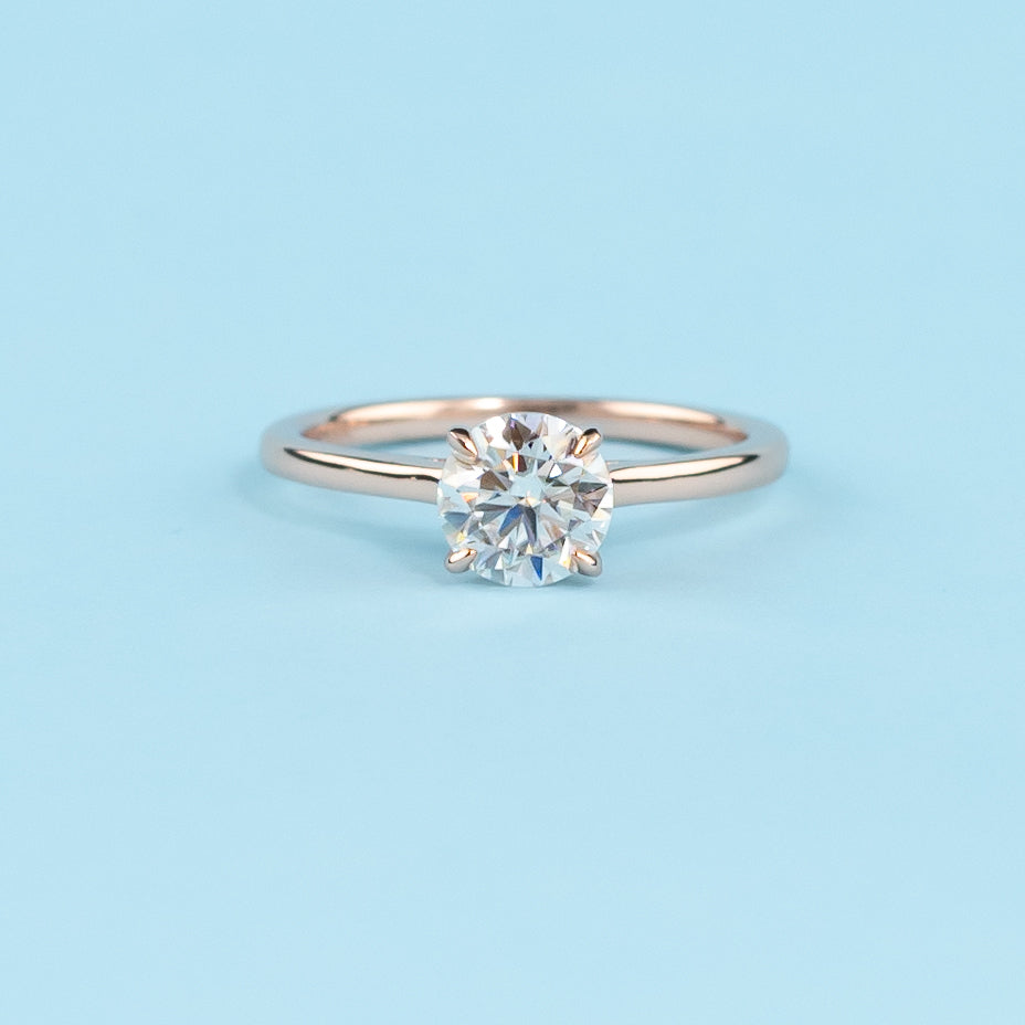Elegant round brilliant moissanite engagement ring with a delicate hidden halo, set in warm 9ct rose gold.