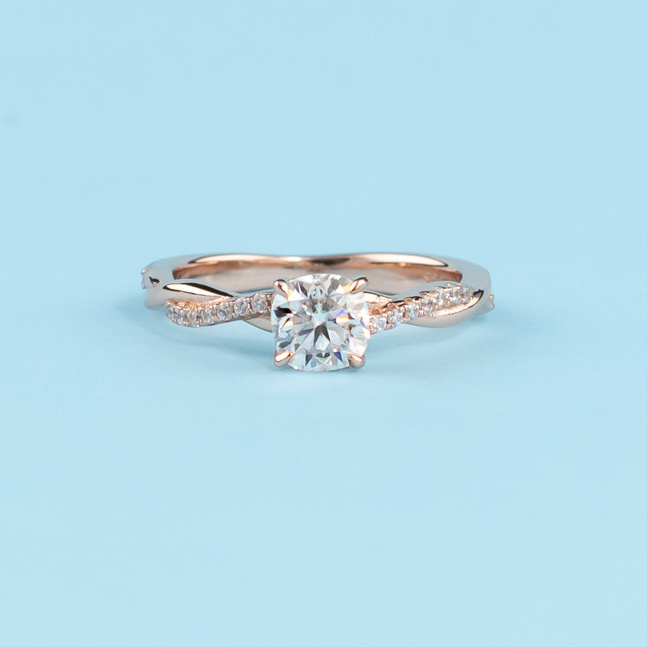 Elegant infinity engagement ring with a cushion cut moissanite, set in warm 9ct rose gold.