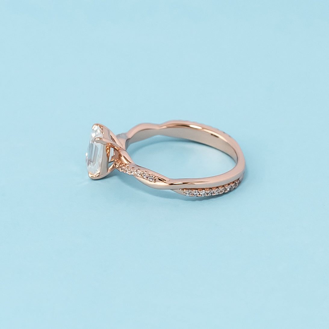 Stunning rose gold engagement ring featuring a sparkling emerald cut moissanite in a classic infinity design.