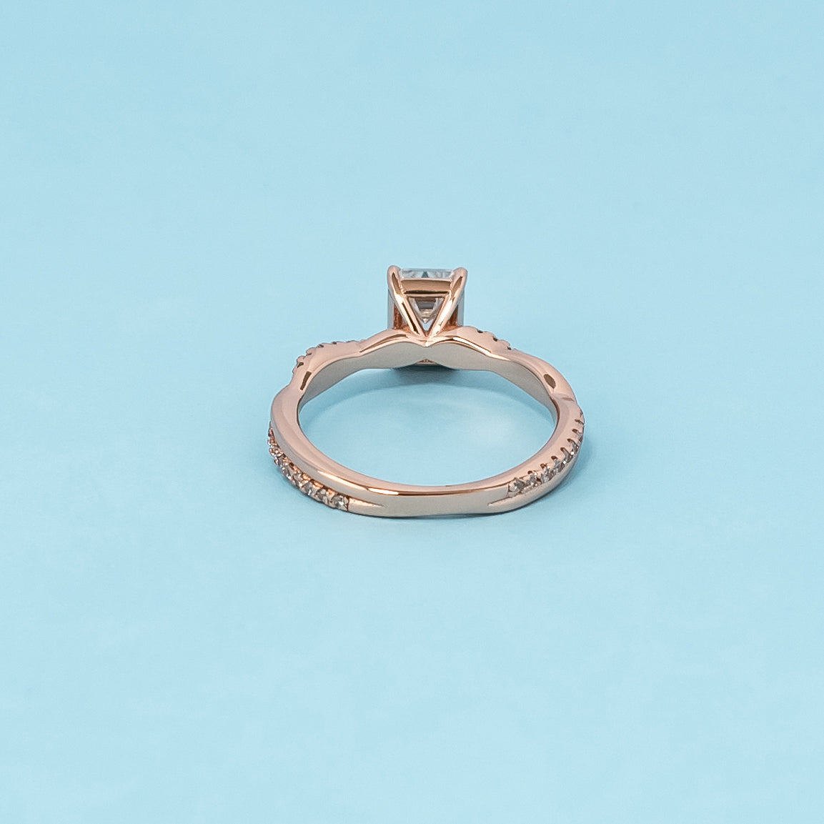 Luxurious 9ct rose gold engagement ring showcasing a beautiful emerald cut moissanite in a timeless infinity setting.