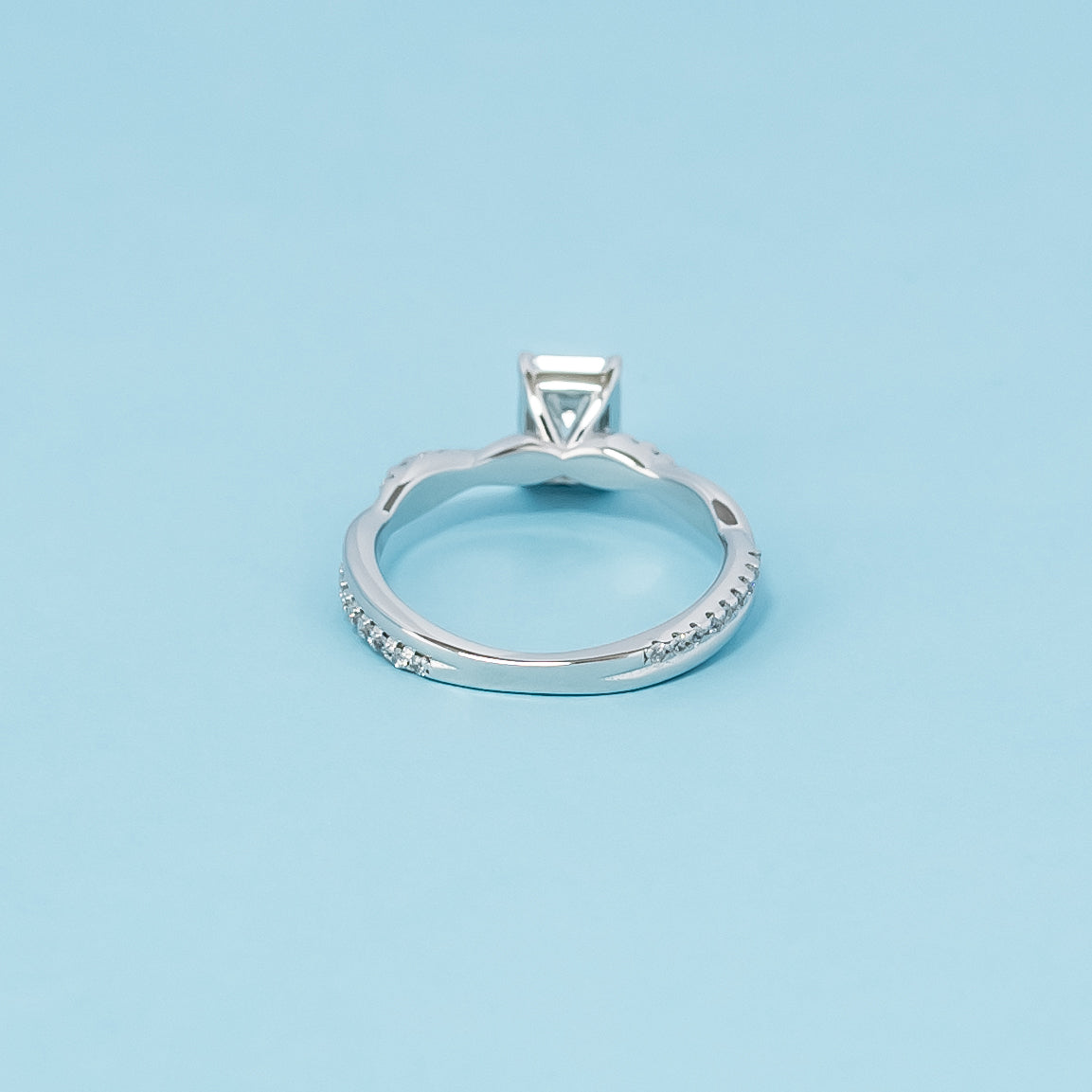 Luxurious 9ct white gold engagement ring with a beautiful emerald cut moissanite in a timeless infinity design, representing everlasting love.