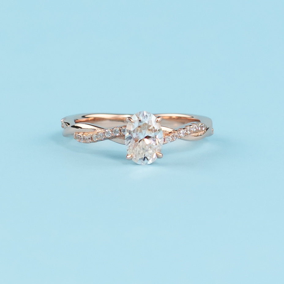 Elegant infinity engagement ring with an oval cut moissanite, set in warm 9ct rose gold.