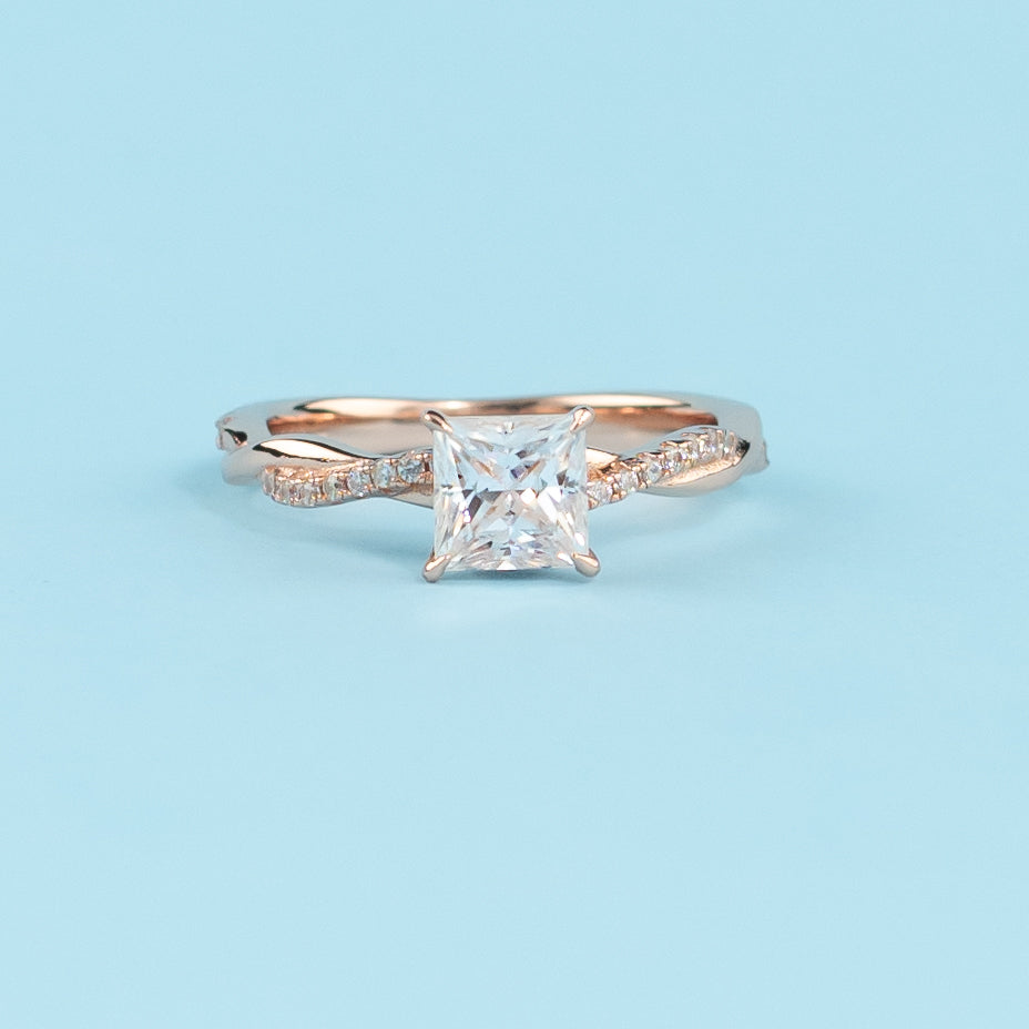 Elegant infinity engagement ring with a princess cut moissanite, set in warm 9ct rose gold.