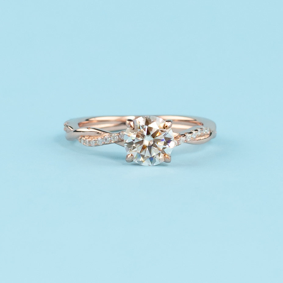 Elegant infinity engagement ring with a round brilliant moissanite, set in warm 9ct rose gold.