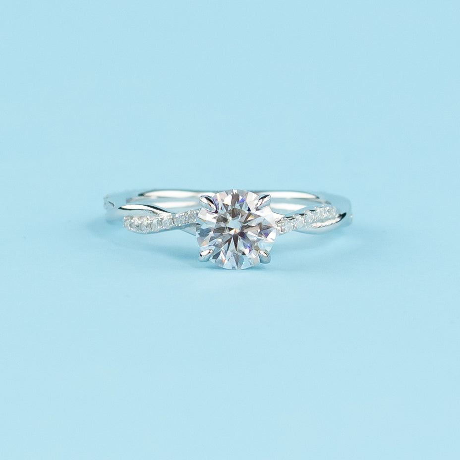 A beautiful round brilliant moissanite engagement ring set in a delicate 9ct white gold band with an infinity design.