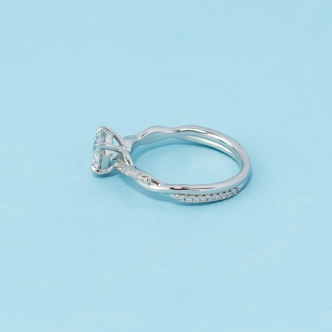 This 9ct white gold engagement ring showcases a sparkling round brilliant moissanite within a timeless infinity setting, representing eternal commitment.