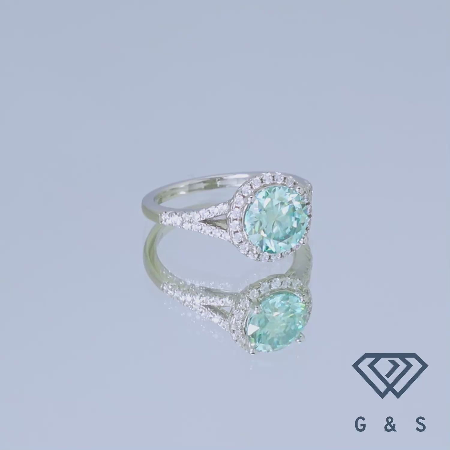 Showcasing a 2.00ct green moissanite in a delicate halo setting, this engagement ring offers a modern twist on classic elegance.