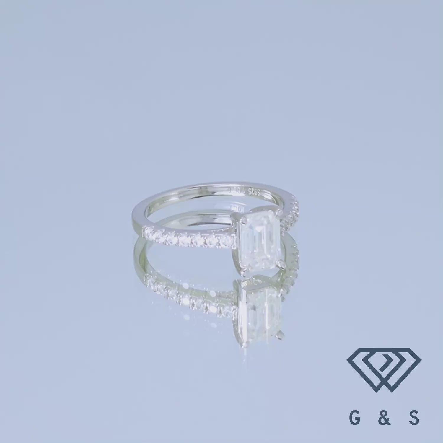 A 1.00ct emerald cut moissanite sits securely in a classic basket setting, highlighting the stone's linear facets.
