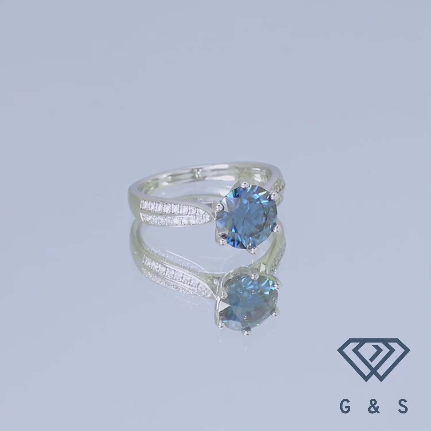 This elegant sterling silver ring showcases a dazzling 2.00ct blue moissanite center stone, enhanced by a sparkling pave band for a touch of classic glamour.