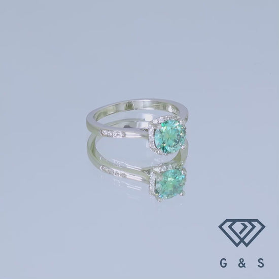 A unique and eye-catching engagement ring showcasing a 1.00ct green moissanite with a modern halo design in polished sterling silver.