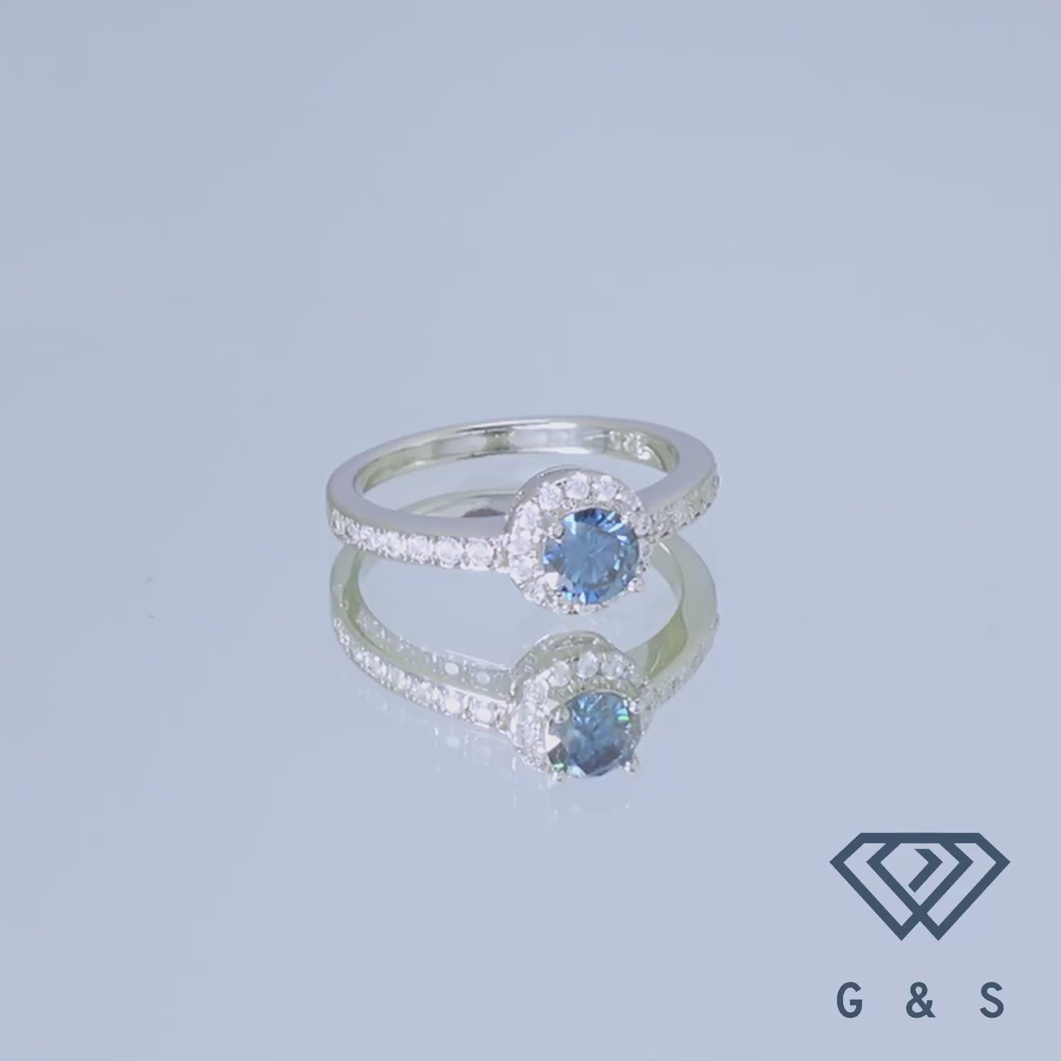 A delicate sterling silver ring showcasing a 0.50ct blue moissanite with a pave halo for added brilliance.