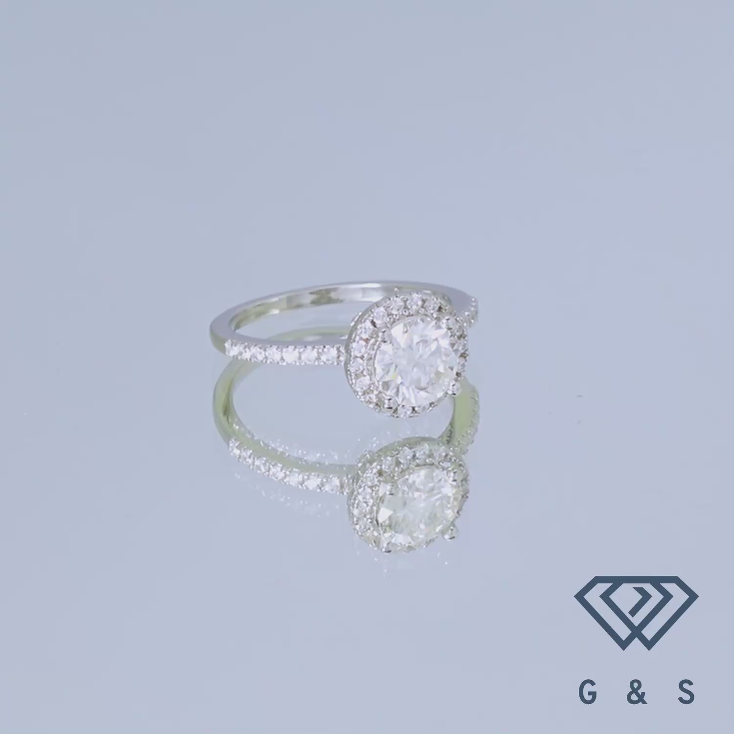 A close up image of a 1.00ct moissanite, surrounded by a classic halo setting, in an engagement ring.