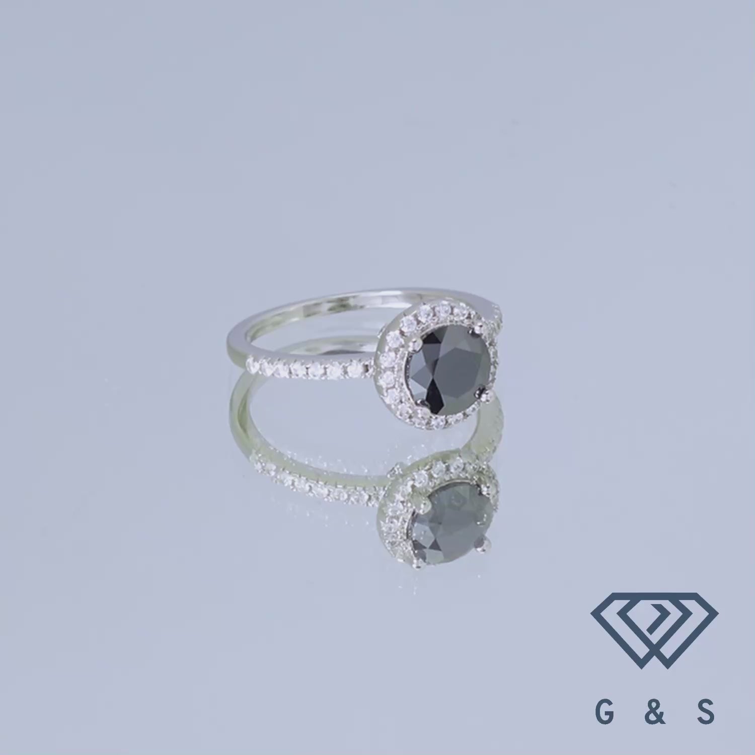 This ring features a bold black moissanite center stone with a classic halo setting, offering a unique and sophisticated alternative to traditional engagement rings.