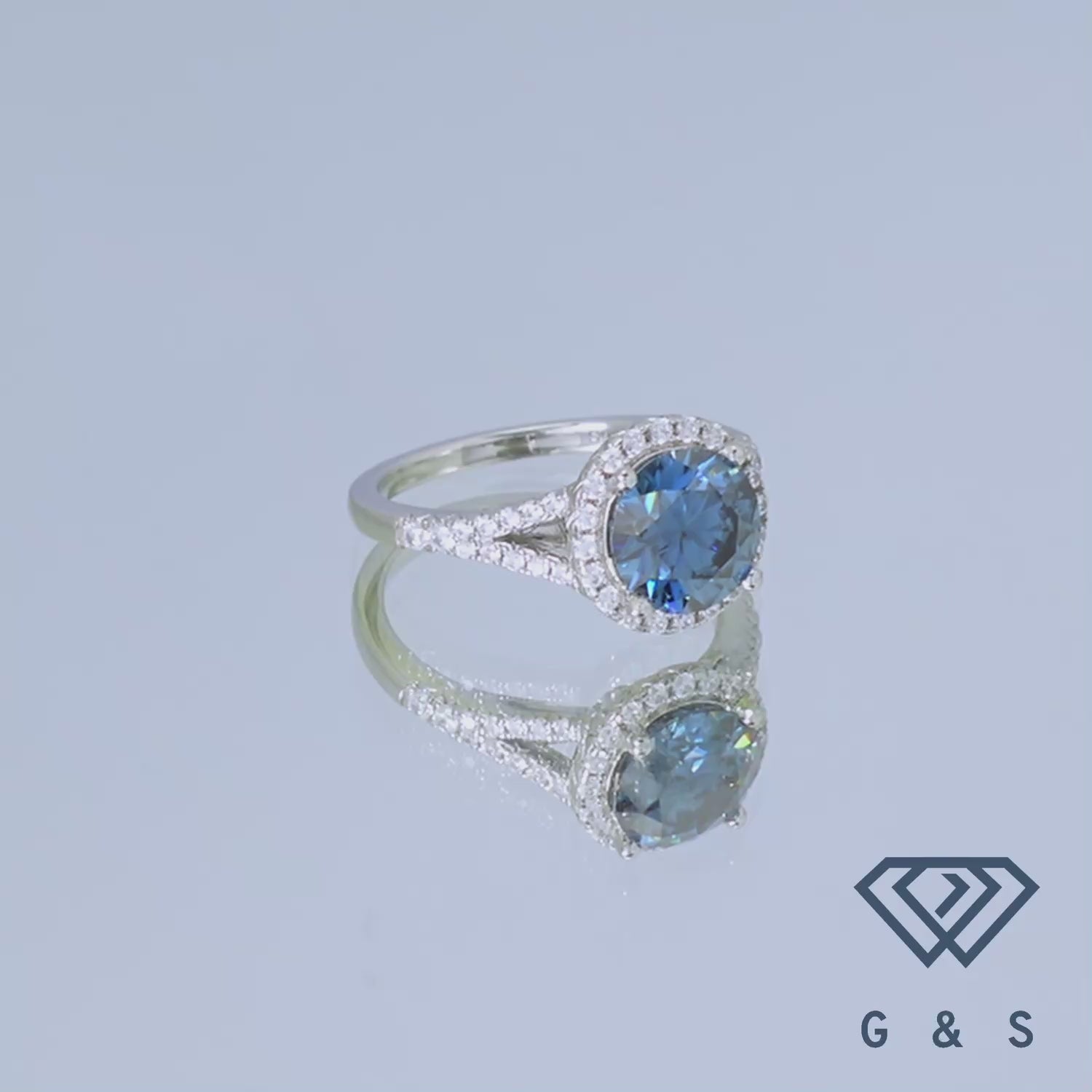This exquisite ring showcases a large, captivating blue moissanite with a dazzling halo, creating a unique and eye-catching design.