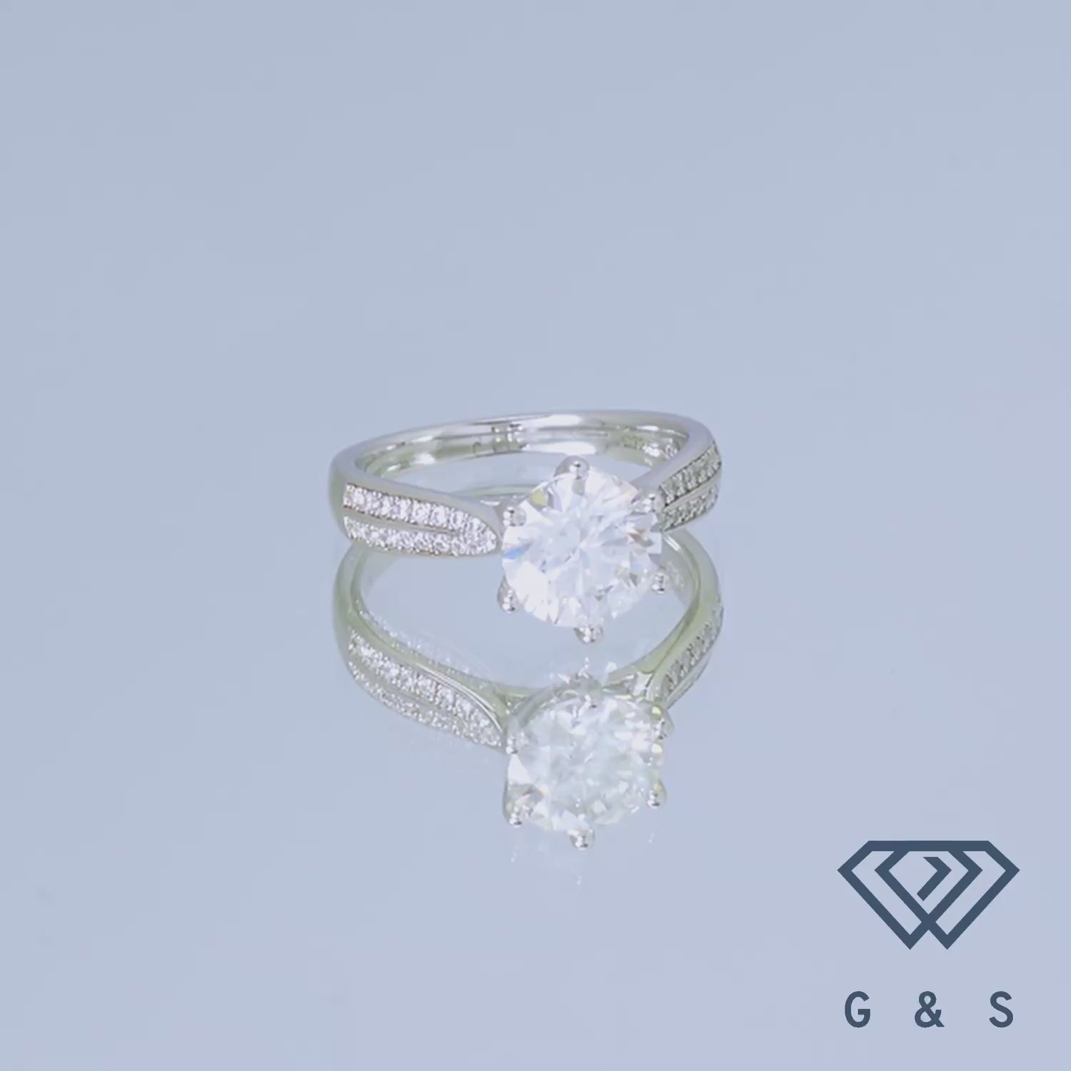 A stunning engagement ring with a large 2 carat moissanite center stone, enhanced by a classic pave setting on a sterling silver band.