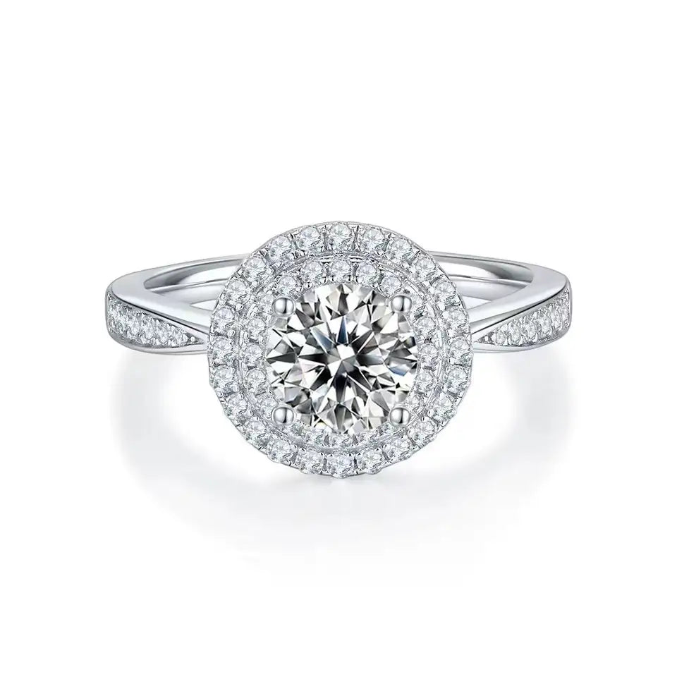 This ring showcases a dazzling 1.00ct round brilliant moissanite center stone, enhanced by a double halo design.