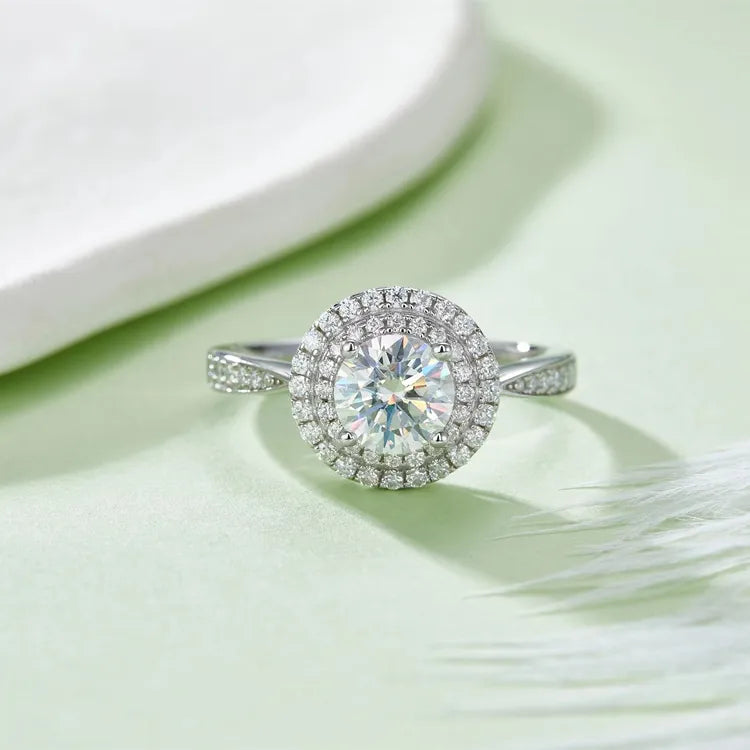 This engagement ring features a classic round brilliant moissanite center stone, accentuated by two glittering halos.