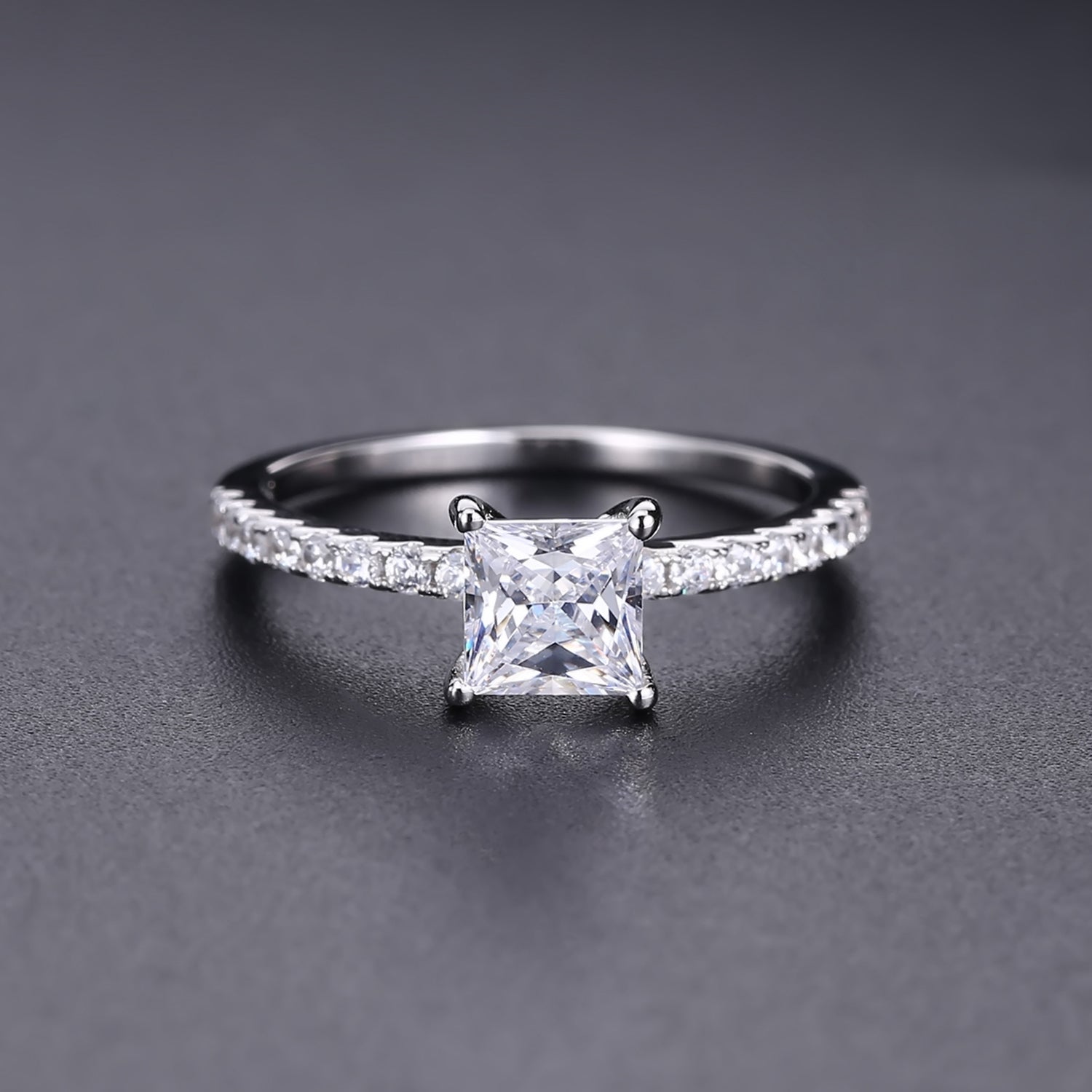 This sterling silver ring showcases a stunning 1.20ct princess cut moissanite as its focal point, perfect for a timeless proposal.