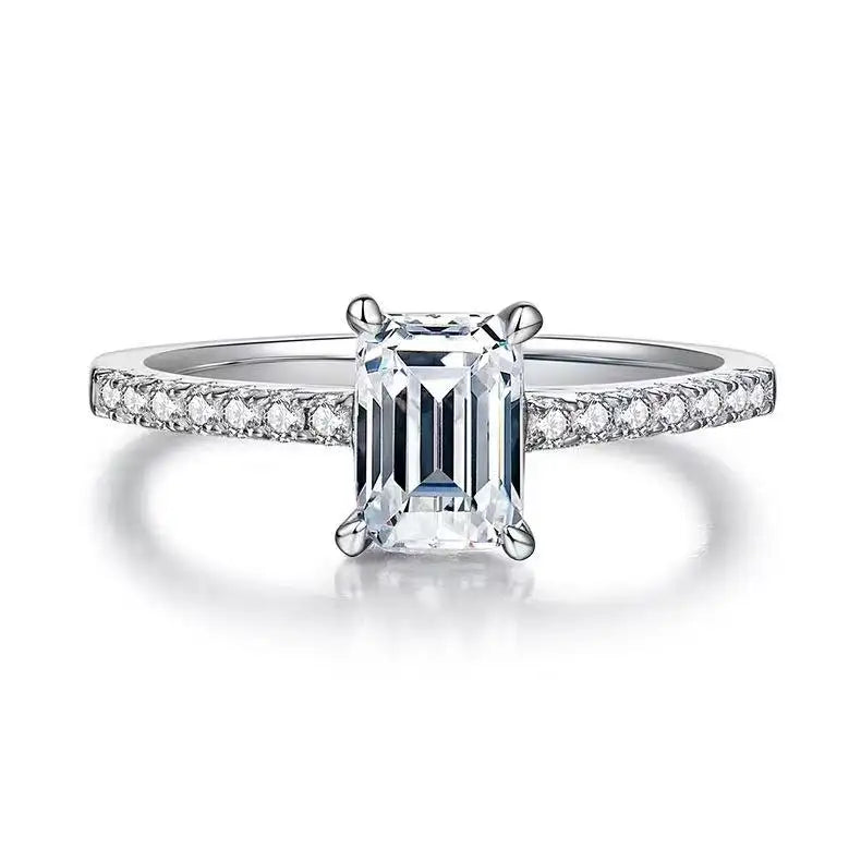 Showcases a beautifully cut 1.00ct emerald moissanite in a refined basket setting, highlighting its clarity and brilliance.