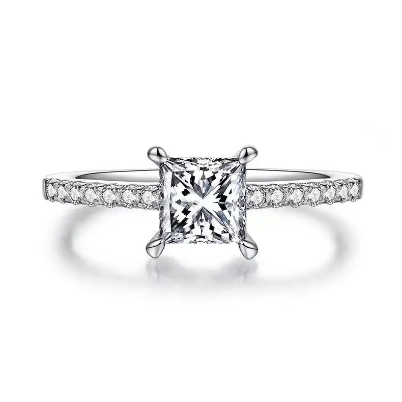 This engagement ring showcases a 1.00ct princess cut moissanite, securely set in a traditional basket style to maximize its sparkle.