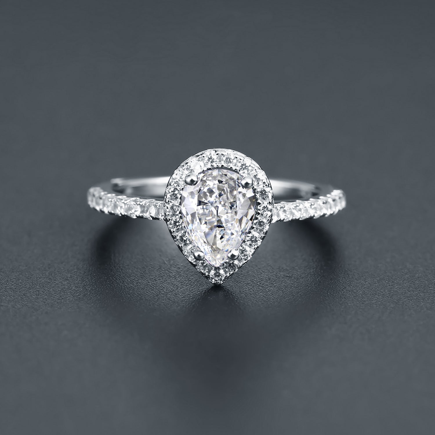 This ring showcases a brilliant 1.25ct pear-cut moissanite embraced by a halo of stones, set in polished sterling silver.